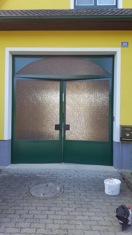 Zweiflügliges Garagentor dunkelgrün lackiert mit Glas-Halbkreis