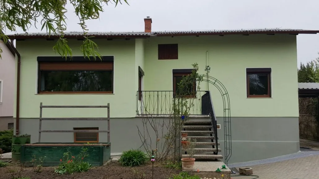Bungalow mit hellgrüner Putzfassade und grauem Sockel — Wohnhaus-Sanierung