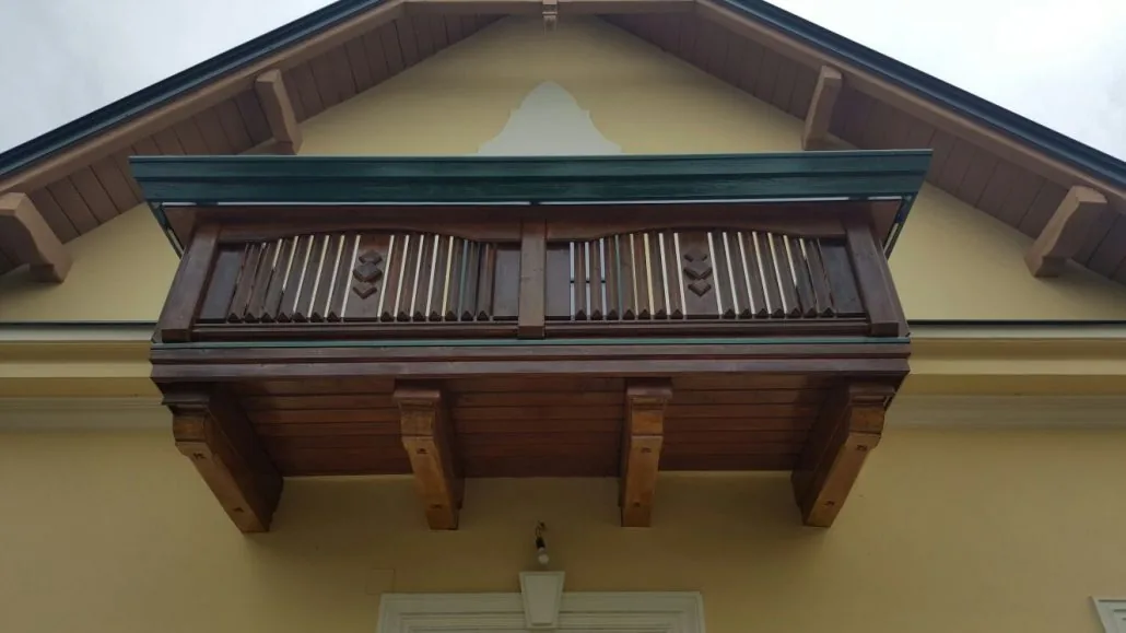 Holz-Zierbalkon mit Konsolen am Giebel frisch lasiert — Altbau-Detail