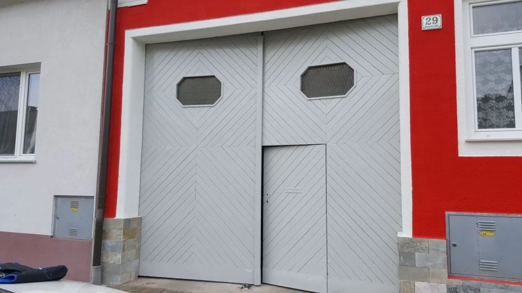 Holz-Einfahrtstor weiß-grau lackiert in roter Putzfassade